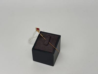 une petite boîte noire ornée d'une broche dorée et rouge
