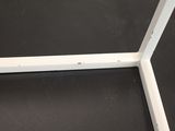 a close up of a white metal frame on a black floor