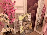 a pink chair in front of a mirror and a pink chair in front of a pink wall with a painting of a buddha