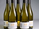 trois bouteilles de vin blanc posées les unes à côté des autres sur une table
