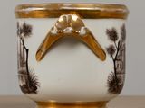 a white and gold vase with a gold handle on a table