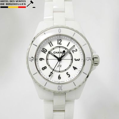 La montre est blanche et son cadran comporte des chiffres noirs.