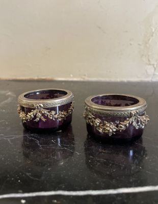une paire de bougeoirs en verre violet posés sur une table en marbre noir