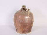 a brown vase sitting on a table with a white wall behind it