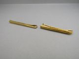 pair of gold plated hair clips on a white surface