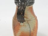 a brown and black vase on a white surface