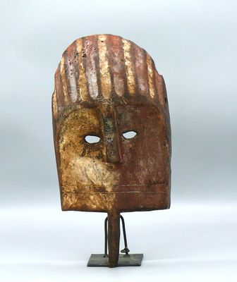 un masque en bois posé sur un socle en métal, sur une surface blanche
