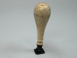un petit vase blanc avec un socle noir posé sur une table