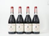 quatre bouteilles de vin sont alignées sur une surface blanche