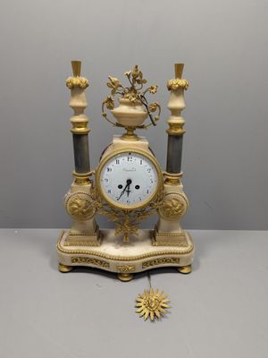 une horloge en or posée sur une table blanche