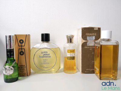 plusieurs flacons de parfum posés sur une table, à côté d'une boîte