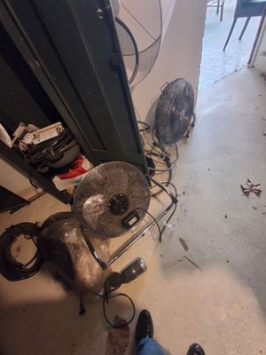 un ventilateur posé par terre à côté d'un autre ventilateur