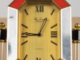 a gold clock with black and red accents on it