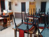 de nombreuses chaises et tables dans une pièce où est accrochée une horloge au mur