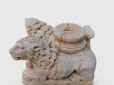 a stone statue of a sheep with a basket of flowers on it ' s back