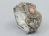 a close up of a silver ring with coral stones on it