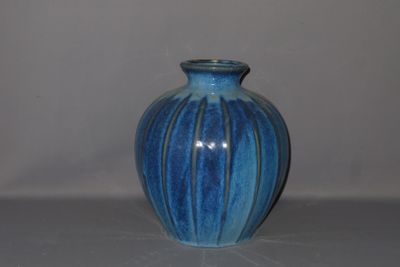 a blue vase sitting on a table with a white wall in the background