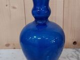 un vase en verre bleu posé sur une table blanche