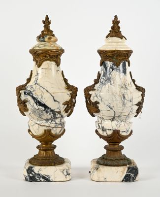 paire d'urnes anciennes en marbre, rehaussées de touches dorées, reposant sur des socles en marbre