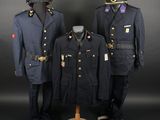 three military uniforms on display in front of a black background