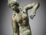 a bronze statue of a woman holding a ball in her right hand
