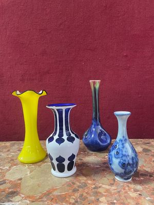 four different colored vases sitting on a table with a red wall in the background