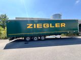 green semi trailer with ziegler logo parked in front of a building