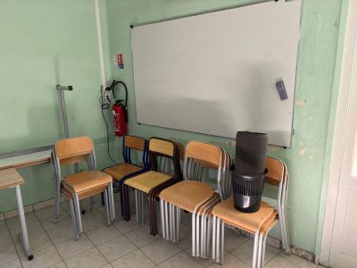 de nombreuses chaises dans une salle de classe avec un tableau blanc accroché au mur