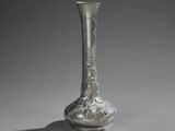 a silver vase sitting on a table with a shadow on the floor