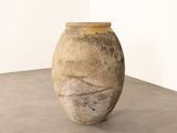 a large vase sitting on a cement floor in a room