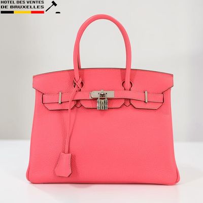 un sac à main en cuir rose muni d'un fermoir métallique sur la poignée