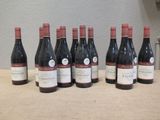 six bouteilles de vin rouge alignées sur une table devant un mur