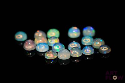 some white oplite beads on a black surface with a black background