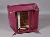 a small pink chair with a book inside of it