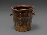 an old brown vase sitting on top of a table next to a gray wall
