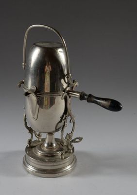 une cafetière ancienne en argent, munie d'une anse et posée sur un socle