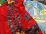 a red dress with black flowers on it on a bed