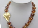 a necklace with a gold leaf on it on a mannequin