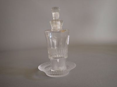 a clear glass bottle with a glass stopper sitting on a plate