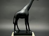 statue d'une girafe debout sur un socle, sur fond gris