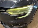 a close up of the front of a black car with a yellow headlight