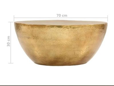le grand bol en or est posé sur une surface blanche