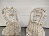 pair of white painted chairs with palm print upholstered seats