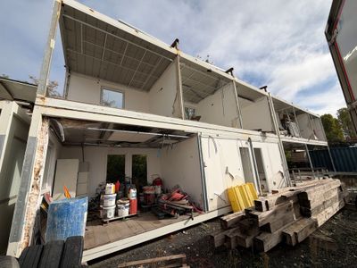 une photo montrant la construction d'une maison-conteneur dans une cour