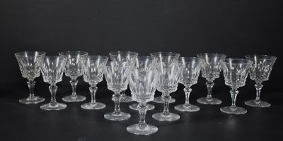douze verres à vin en cristal alignés sur une surface noire