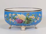 un bol bleu orné de fleurs peintes, posé sur un socle