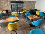 brightly colored chairs and tables in a restaurant with a brick wall