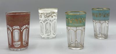 quatre verres de couleurs différentes sont alignés sur une surface blanche