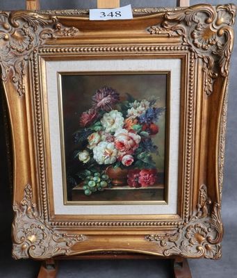 une peinture à l'huile représentant des fleurs, dans un cadre doré, posée sur un chevalet