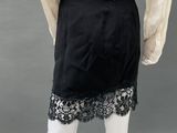 a woman ' s black skirt with a beige shirt and black lace trim
